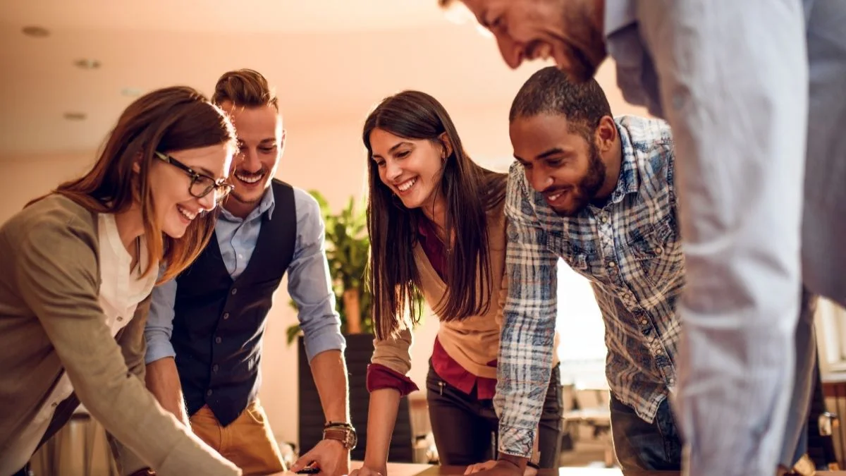 Lachendes Team arbeitet gemeinsam in einem hellen Innenraum
